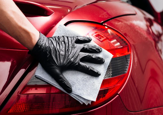 Koplamp reinigen met microvezeldoek op rode auto – Auto detailing service